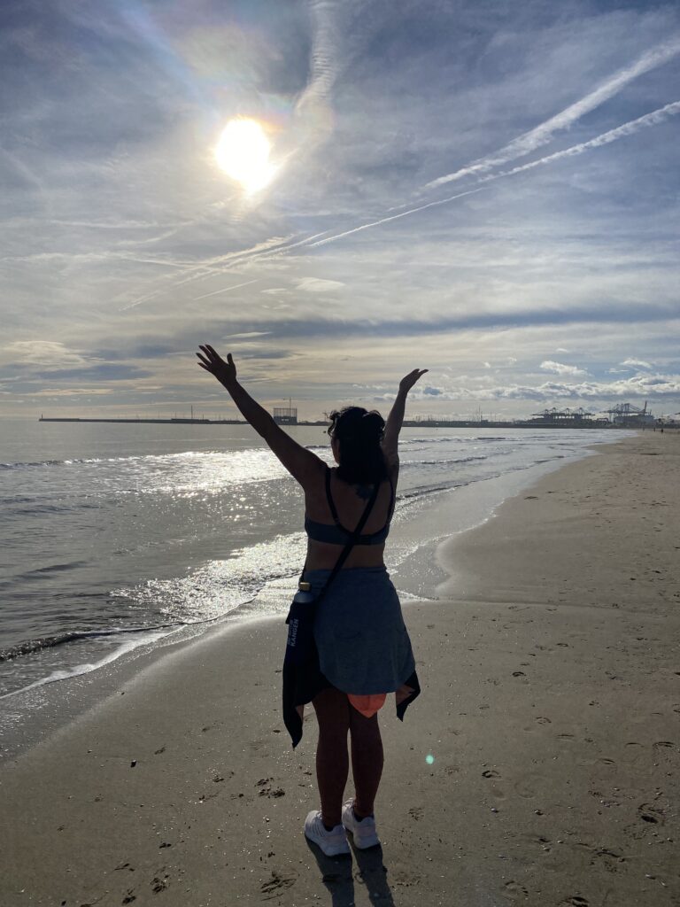 Mujer frente al mar en un proceso de duelo perinatal, abriendo los brazos hacia la luz con esperanza tras la pérdida de un bebé