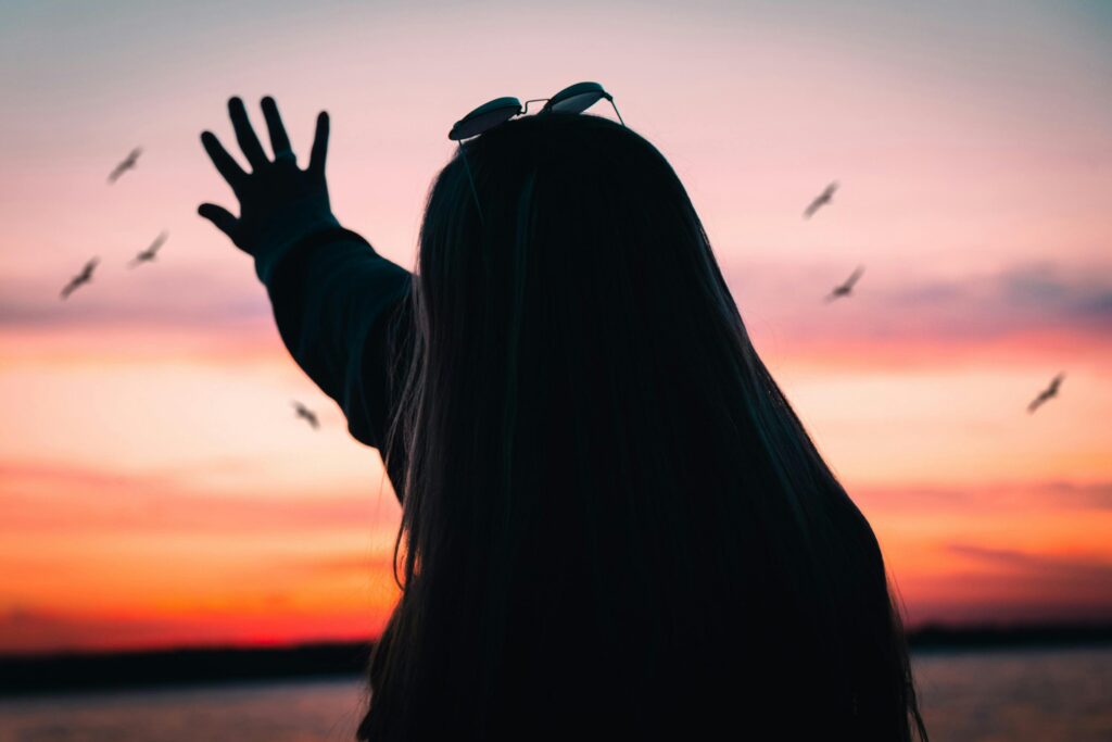Mujer contemplando el atardecer mientras reflexiona sobre el duelo, la paz interior y el aprendizaje de soltar