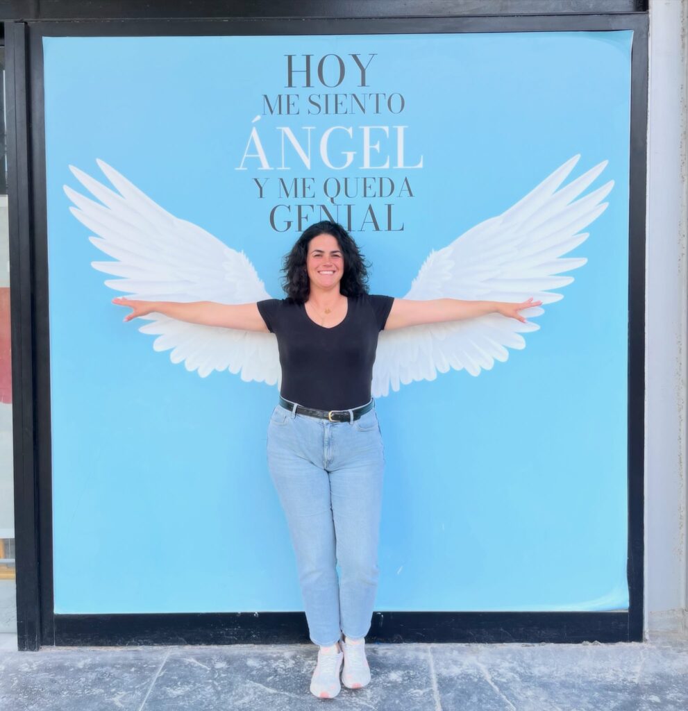 Mujer sonriendo frente a unas alas blancas que simbolizan esperanza, acompañamiento y transformación en el duelo perinatal.