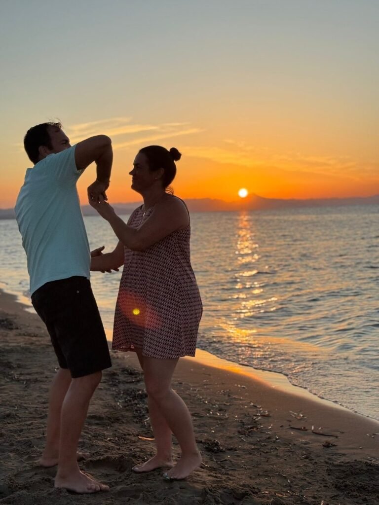 Ana Belén y su pareja bailando en la orilla de la playa al atardecer